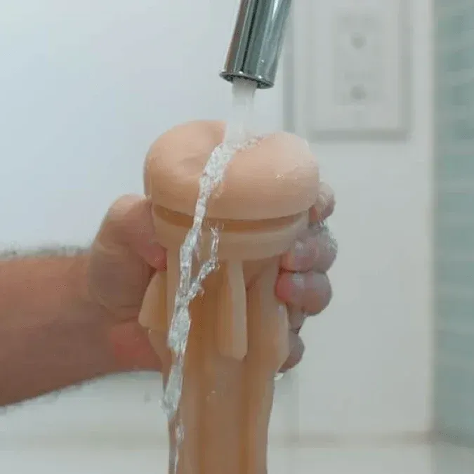 Rinsing a Fleshlight sleeve under warm running water at a sink